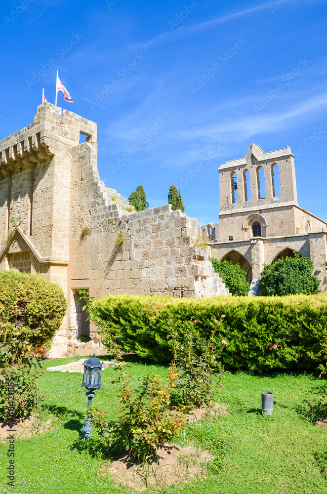 Vertical photo of medieval Bellapais Abbey in Turkish Northern Cyprus. Captured with the adjacent park and with blue sky. Significant historical site and popular tourist attraction