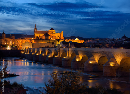 Roman Bridge over the Guadalquivir River with Episcopal Palace and Cordoba Cathedral at dusk