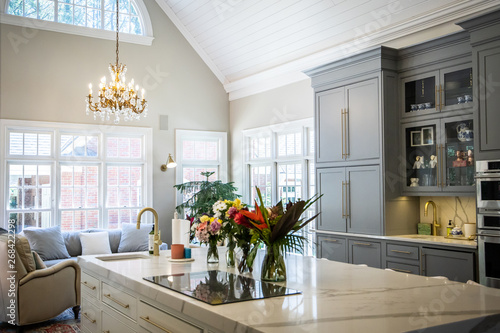 Open Concept Elegant and Spacious Kitchen with Marble Countertops, Chandelier, and Two Toned Cabinets photo