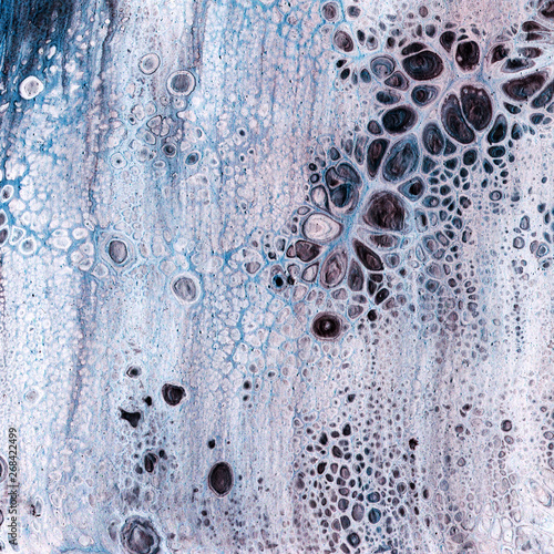 Very beautiful texture background. White paint flows in blue with the addition of black paint. Style includes curls of marble or agate with bubbles and cells. Natural style.