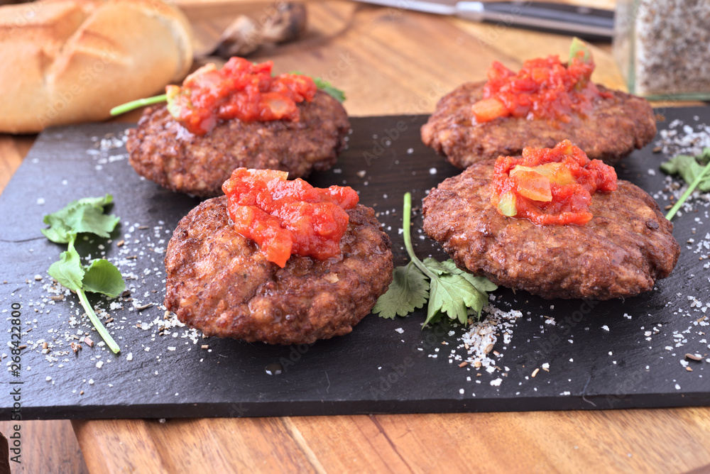 Handmade burgers with homemade tomato sauce on black stone