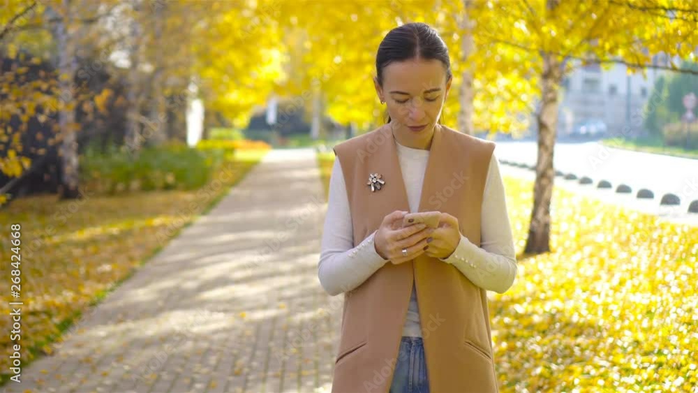 Fall concept - beautiful woman drinking coffee in autumn park under fall foliage Fall concept - beautiful woman drinking coffee in autumn park under fall foliage