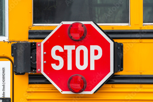 Close up of an octagon shaped red stop sign with signal lights on a school bus