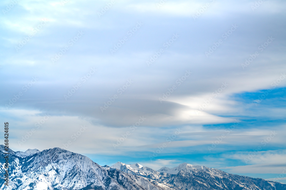 Striking mountain with rugged slopes under vast blue sky with clouds