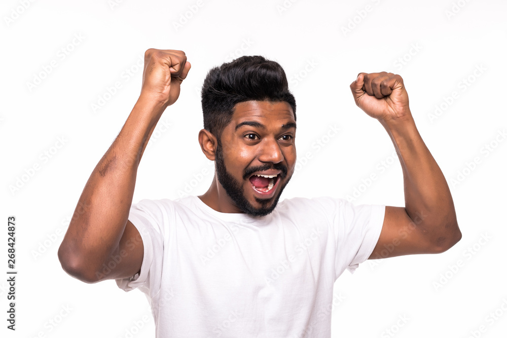 Fototapeta premium I won. Happy young indian man gesturing and smiling while standing against white background