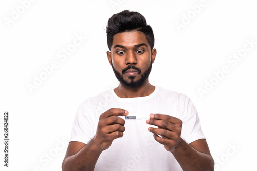 People, healthcare and fever concept - unhealthy indian man look shocked at measuring temperature by thermometer over white background
