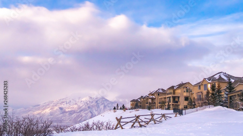 Clear Panorama Homes overlooking a scenic snow capped mountain and vivid blue sky with clouds © Jason