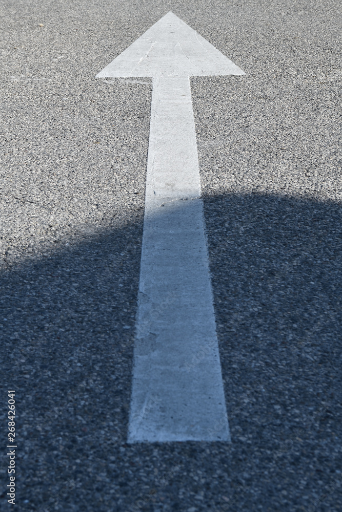 Asphalt sign: white arrow on the concrete texture Asphalt sign: white arrow on the concrete texture