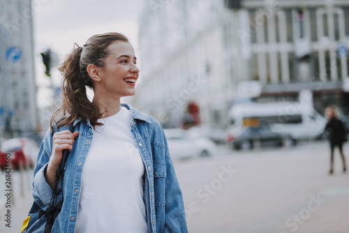 Pretty smiling young female walking around city