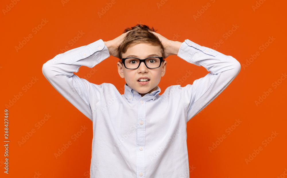 Shocked teen boy in glasses touching his head in amazement Shocked teen boy in glasses touching his head in amazement
