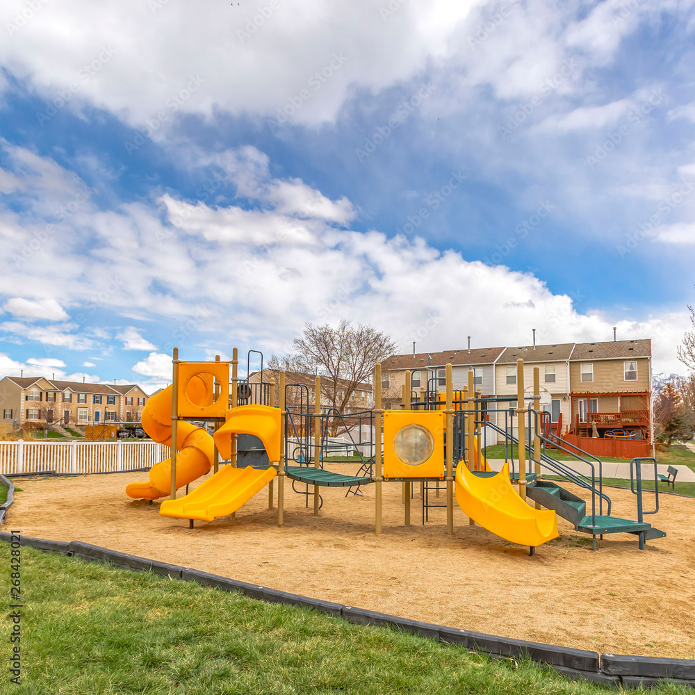 Square Colorful slides at a playground with homes and cloudy sky in the background