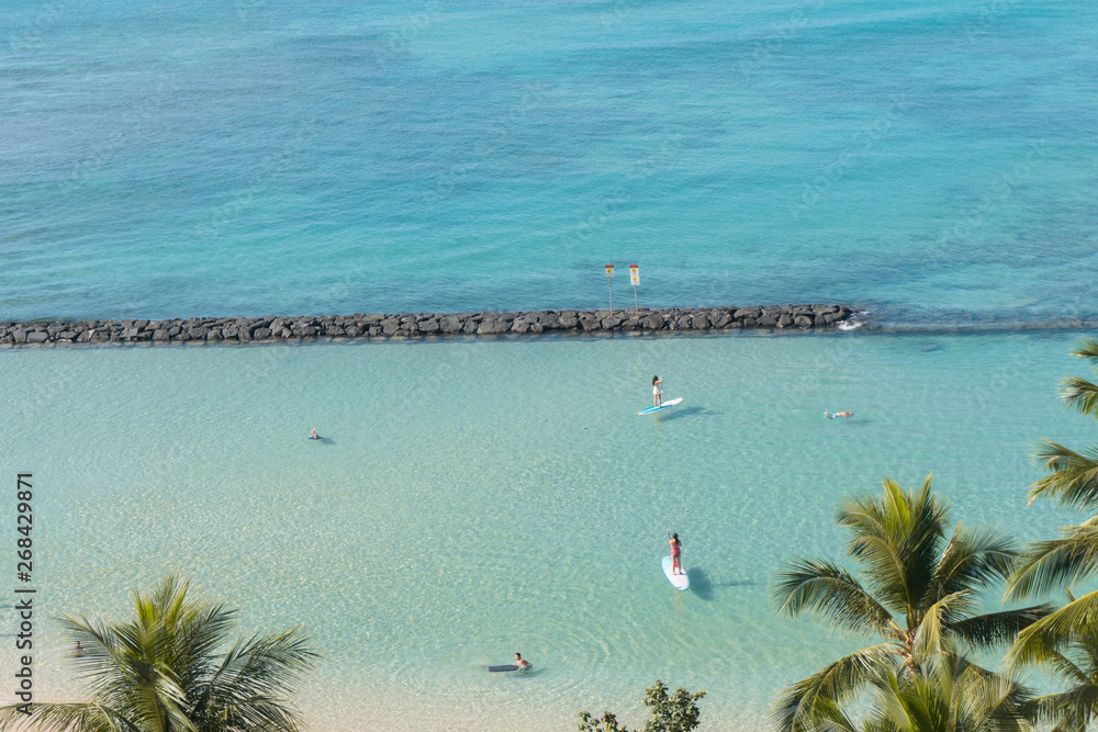 HONOLULU, USA: High angle view of Waikiki Beach in Hawaii. Turquoise sea, palm trees and stand-up paddle.