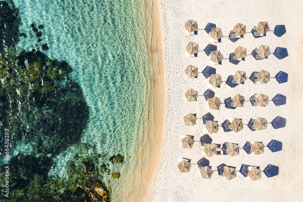 View from above, stunning aerial view of a white beach with beach umbrellas and turquoise clear sea. Emerald Coast, Sardinia, Italy.
