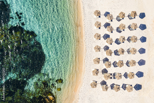 View from above, stunning aerial view of a white beach with beach umbrellas and turquoise clear sea. Emerald Coast (Costa Smeralda), Sardinia, Italy.