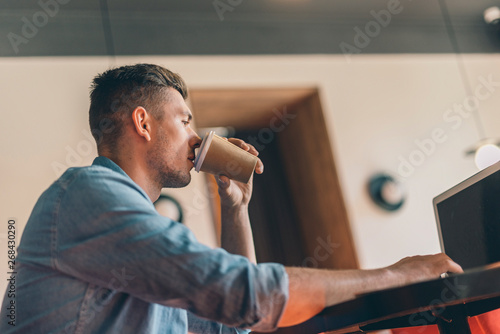 Thoughtful young man drinking coffee and looking at the screen