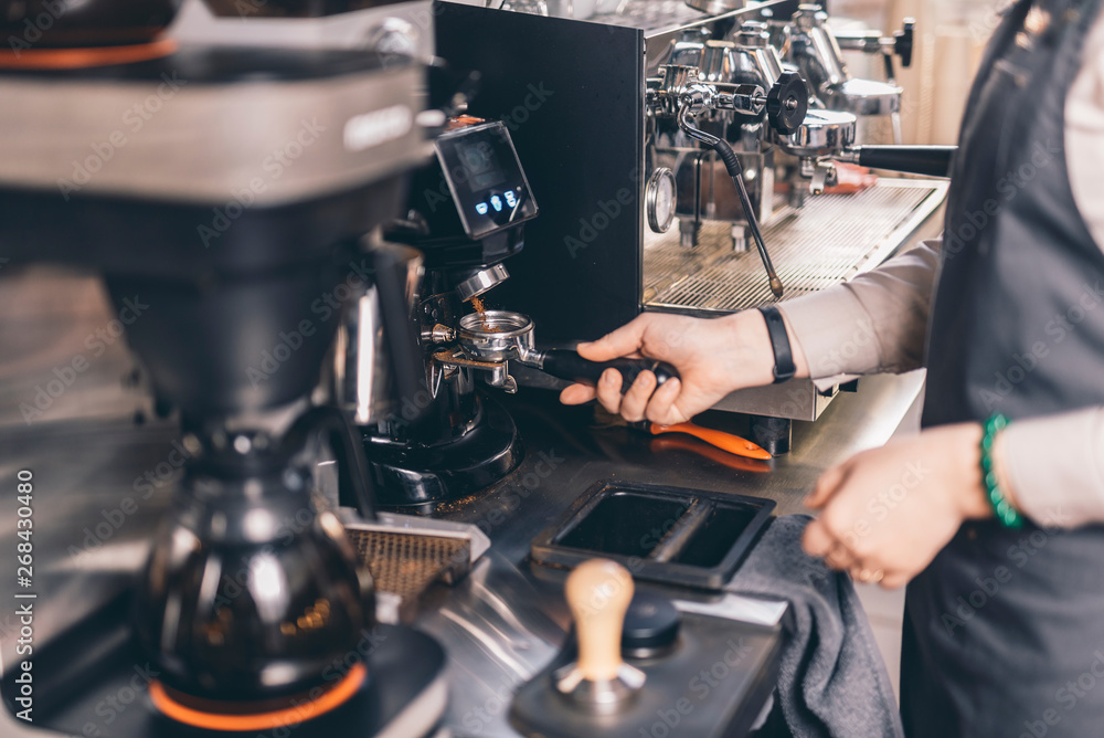 Hand of barista holding portafilter with coffee in it