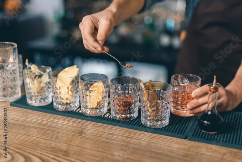 Glasses of spices and hand of barista holding tea spoon