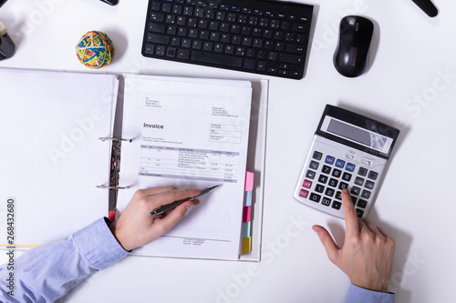 Businessman Using Calculator While Calculating Invoice
