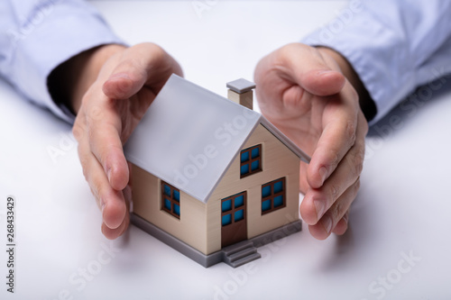 Man's Hand Protecting Model House