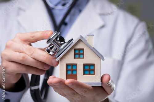 Doctor Using Stethoscope To Check Model House