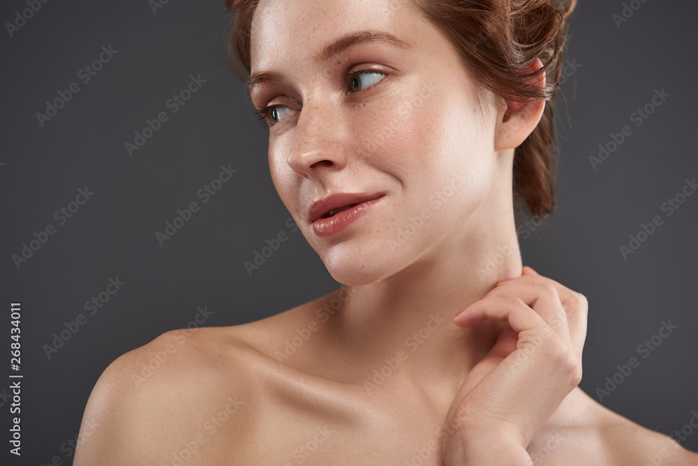 Charming red-haired girl with freckles touching her neck Charming red-haired girl with freckles touching her neck