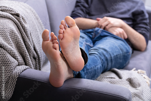 Man Relaxing On Sofa With His Legs