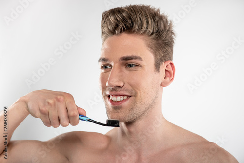 Handsome young man with stubble holding toothbrush