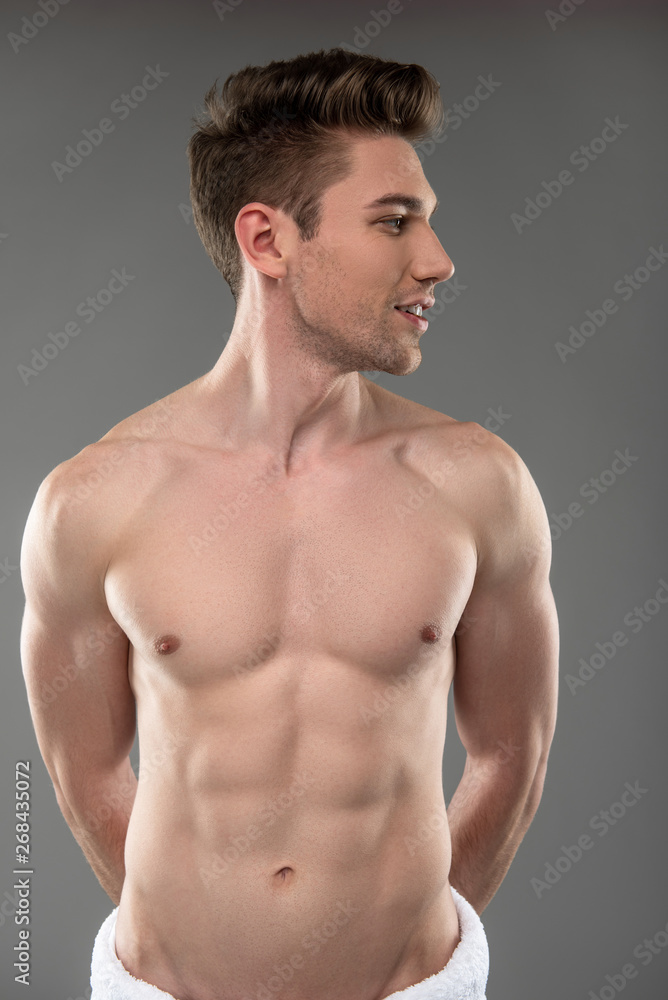Handsome young man with perfect body standing against blue-gray background Handsome young man with perfect body standing against blue-gray background