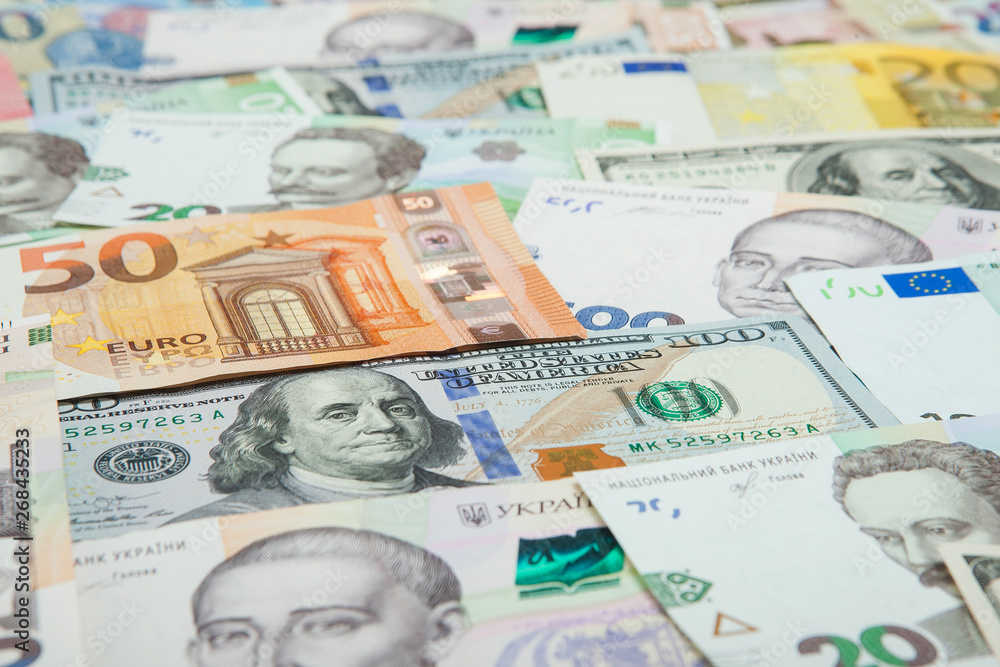 Money and finances concept. One hundred dollar new bill on colorful abstract background of Ukrainian, American and euro national currency banknotes Money and finances concept. One hundred dollar new bill on colorful abstract background of Ukrainian, American and euro national currency banknotes