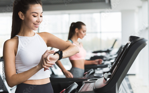 Girl checking heart rate, running on treadmill