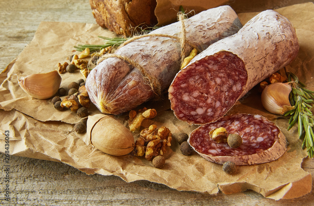 French salami and walnuts on craft paper on wooden background French salami and walnuts on craft paper on wooden background