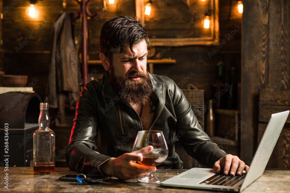 Portrait of a handsome man with beard. Brutality and masculine concept. Barbershop, shaving.Macho is drinking by his laptop. Disgust. Portrait of a handsome man with beard. Brutality and masculine concept. Barbershop, shaving.Macho is drinking by his laptop. Disgust.