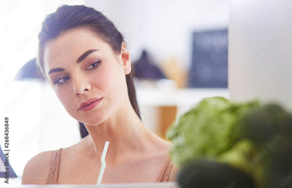 Young woman with glass of tasty healthy smoothie at table in kitchen Young woman with glass of tasty healthy smoothie at table in kitchen