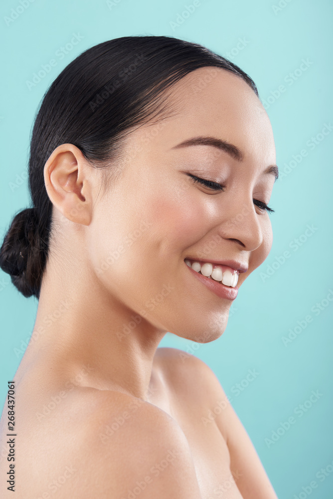 Close up of young Asian lady posing for camera against blue background Close up of young Asian lady posing for camera against blue background