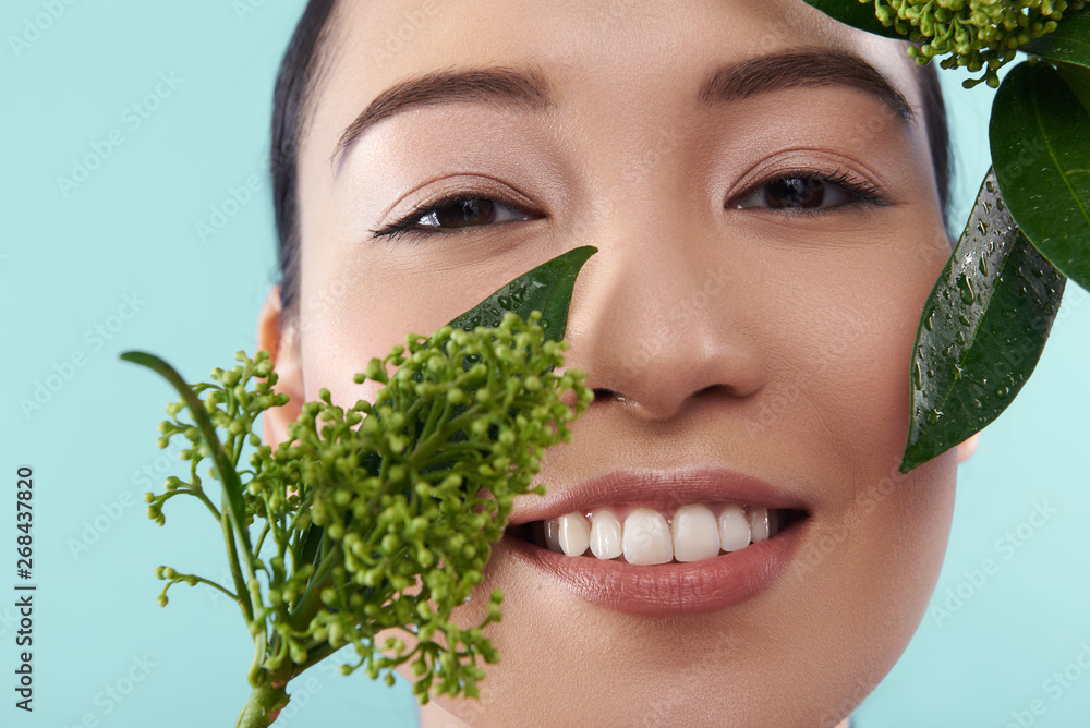 Portrait of happy Asian lady posing with branch of plant Portrait of happy Asian lady posing with branch of plant
