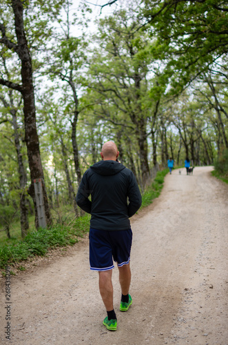 Young man seen from back dressed in sports walking quietly on a path through the woods