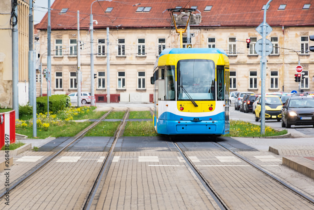 Obraz premium Colourful tram runs on tramway track over green grass area in Kosice (SLOVAKIA)
