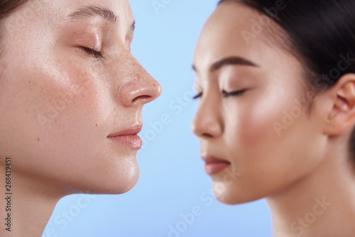 Close up of pretty interracial women situating in studio