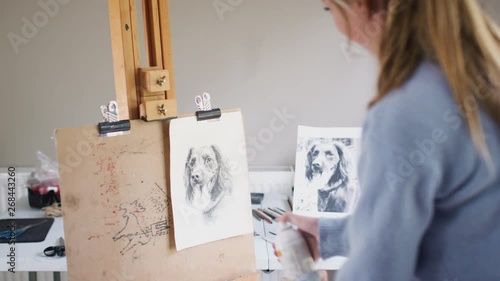 Female Teenage Artist Spraying Lacquer Fixative Onto Drawing Picture Of Dog In Charcoal