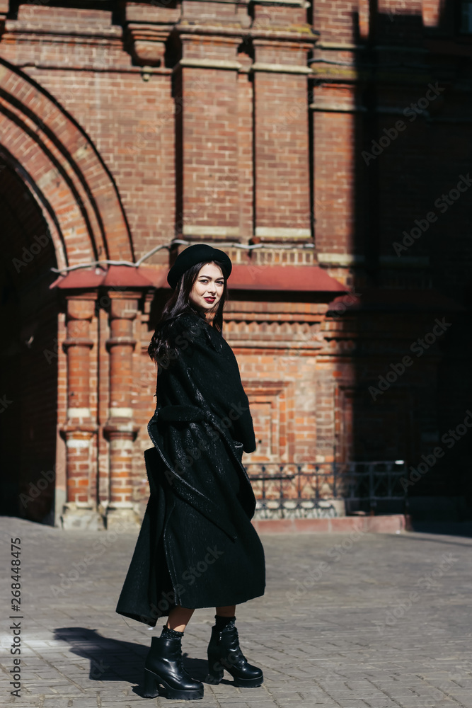 A girl in a black coat walks down the street A girl in a black coat walks down the street