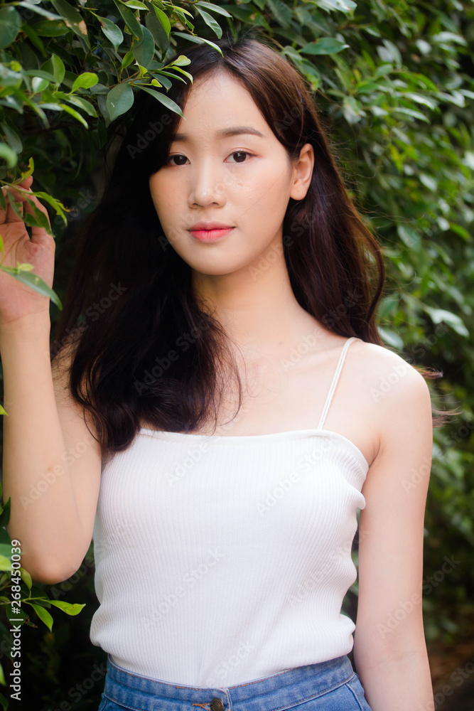 Portrait of thai china adult beautiful girl White shirt blue jeans relax and smile Portrait of thai china adult beautiful girl White shirt blue jeans relax and smile