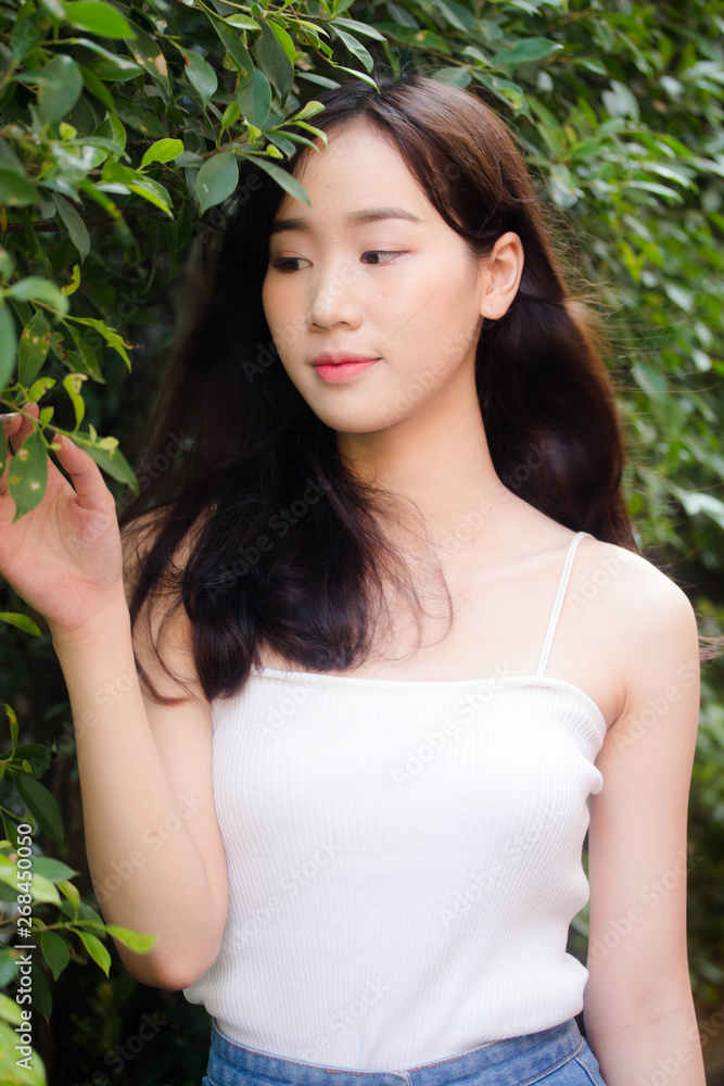 Portrait of thai china adult beautiful girl White shirt blue jeans relax and smile Portrait of thai china adult beautiful girl White shirt blue jeans relax and smile