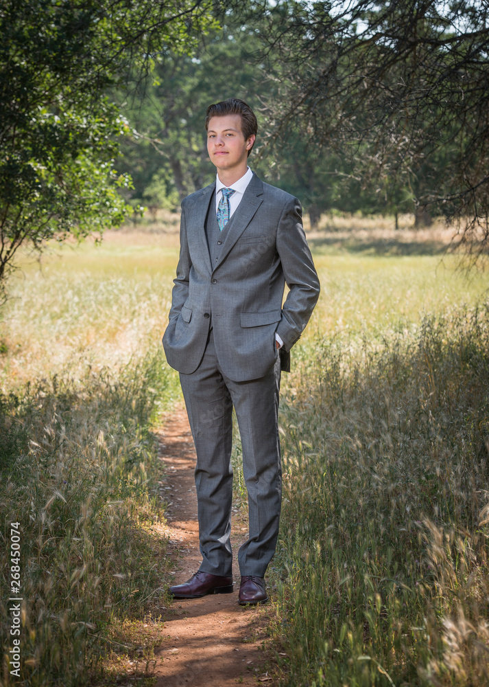 Confident young man standing outside in business suit, hands in pockets Confident young man standing outside in business suit, hands in pockets