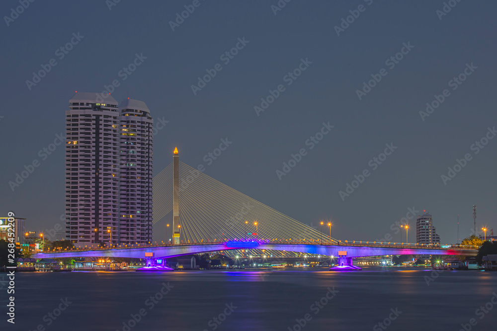 The beauty of colorful lights on Pinklao bridge and cars driving at Night on Chao Phraya River, Bangkok in Thailand.