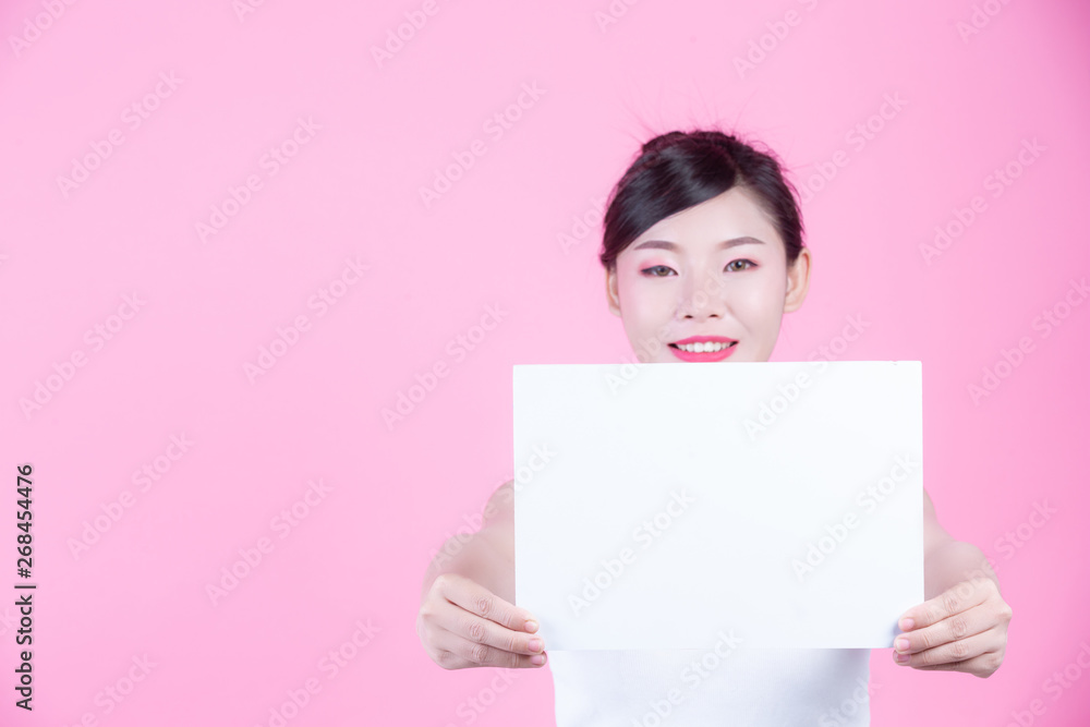 Beautiful woman holding a white board sheet on a pink background. Beautiful woman holding a white board sheet on a pink background.