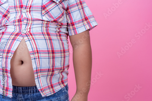 Obese boy who is overweight on a pink background.