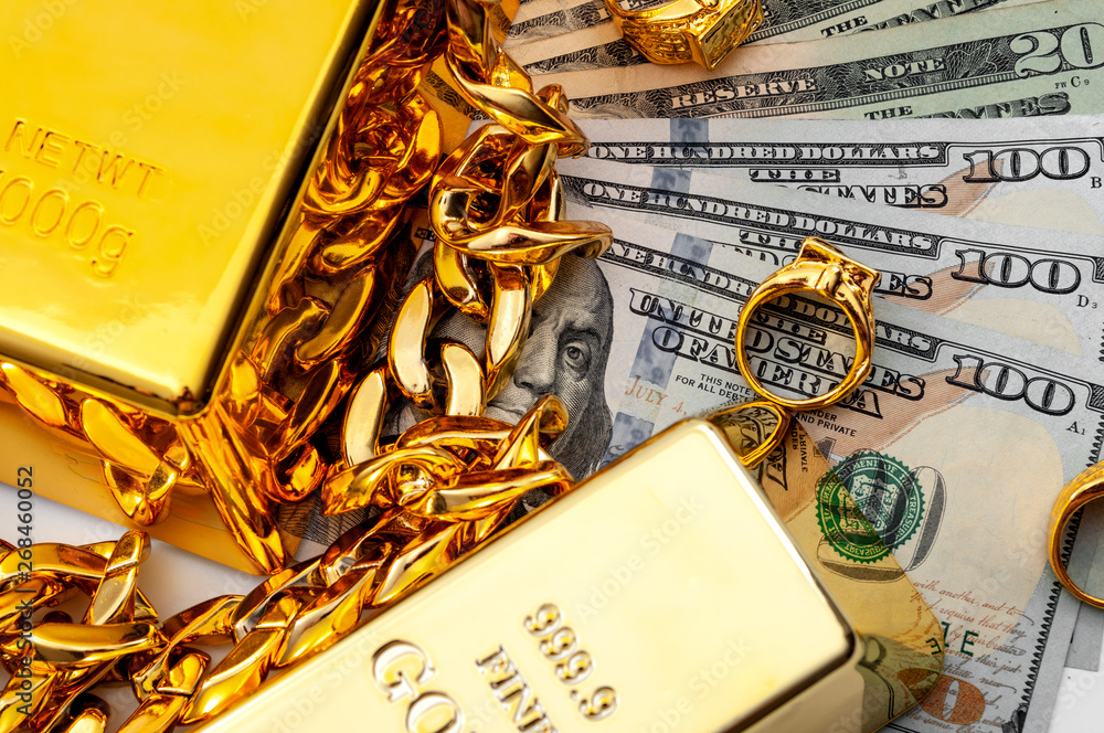 Jewelry buyer, pawn shop and buy and sell precious metals concept theme  with a pile of cash in US dollars, golden rings, necklace bracelet and gold  bullion isolated on white background Stock