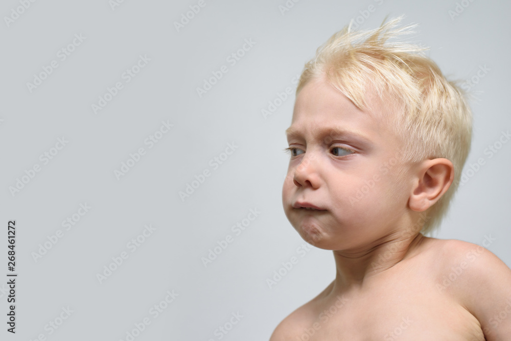 Small blond boy looking with suspicion. Portrait. Space for text Small blond boy looking with suspicion. Portrait. Space for text