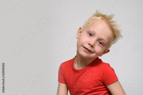 Little smiling blonde boy in red t-shirt. Portrait. Space for text. White background