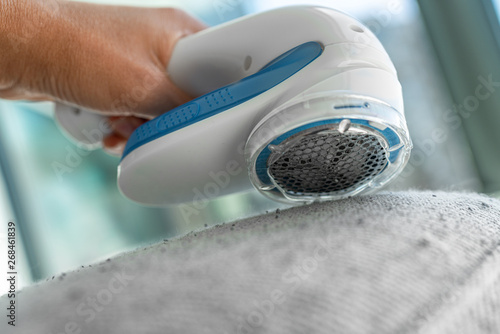 Quadro em tela Fabric shaver fuzz remover woman removing lint on fabric sofa furniture at home with handheld electric defuzzer